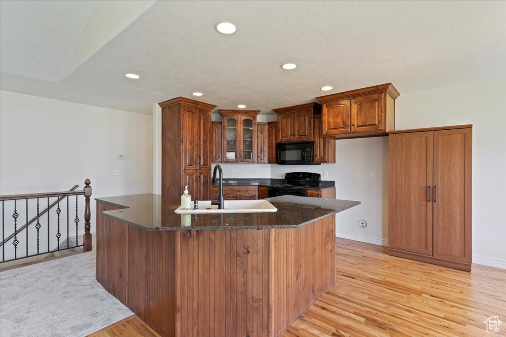 Kitchen featuring black appliances, a sink, brown cabinetry, recessed lighting, and light wood finished floors