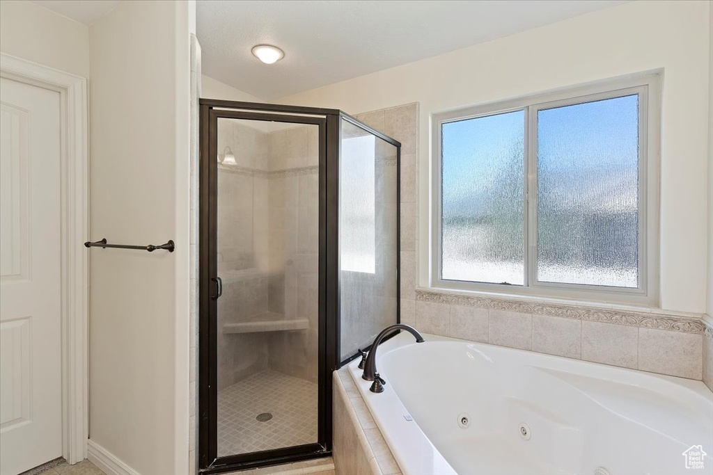 Bathroom featuring a shower stall and a tub with jets