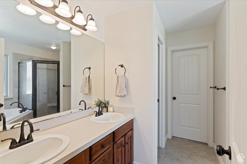 Bathroom featuring a shower stall, a garden tub, and double vanity