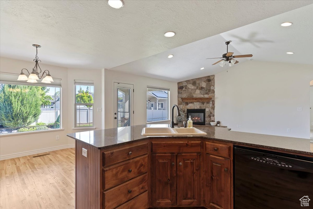 Kitchen featuring dishwasher, a sink, a fireplace, light wood-style flooring, and a ceiling fan