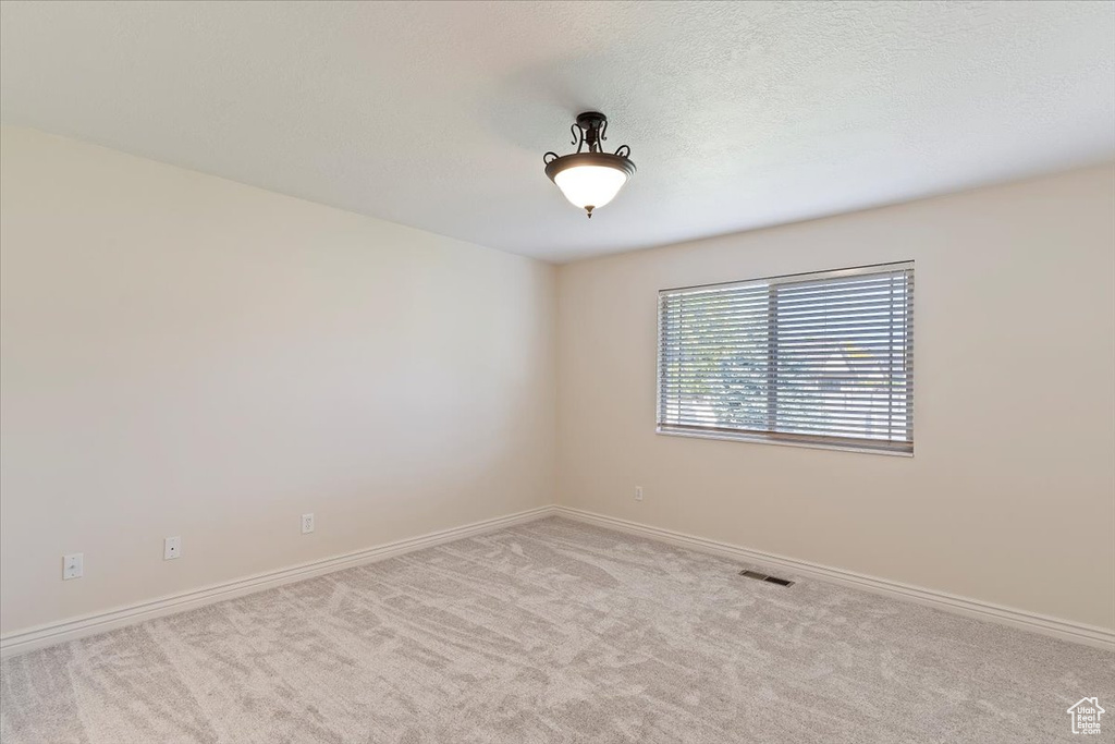 Spare room featuring carpet and baseboards