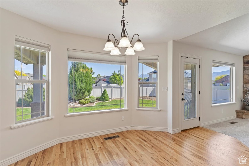Unfurnished dining area with baseboards, a chandelier, and wood finished floors