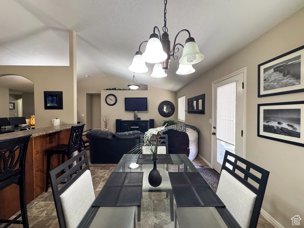 Dining area featuring an inviting chandelier, vaulted ceiling, baseboards, and arched walkways