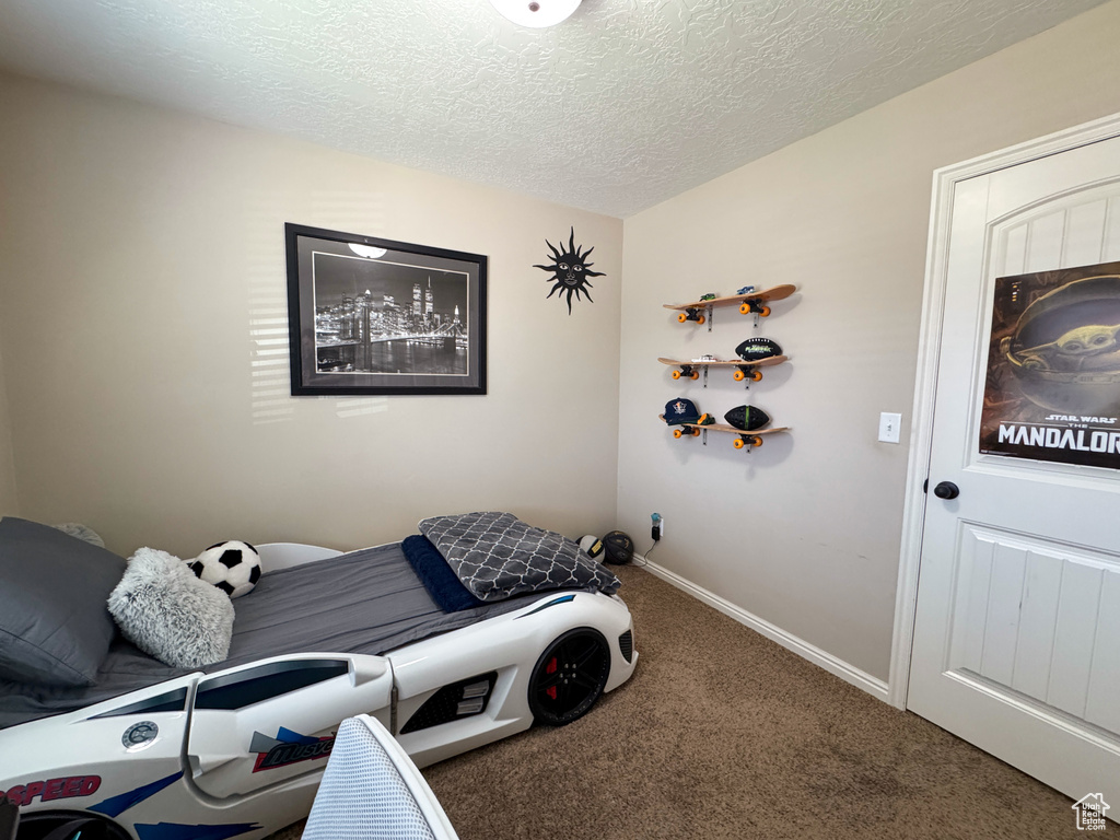 Carpeted bedroom with a textured ceiling and baseboards
