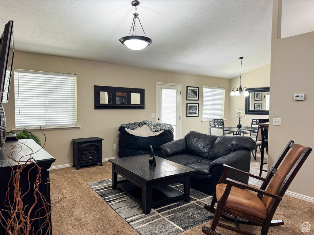 Living room with baseboards, carpet flooring, an inviting chandelier, and a wood stove