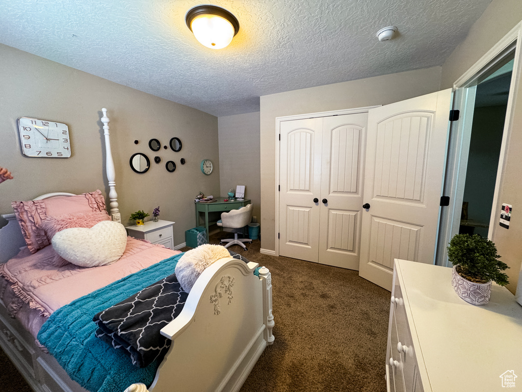 Bedroom with dark carpet, a closet, and a textured ceiling