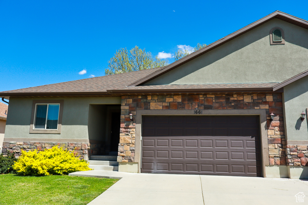 Ranch-style home with stone siding, an attached garage, stucco siding, concrete driveway, and roof with shingles