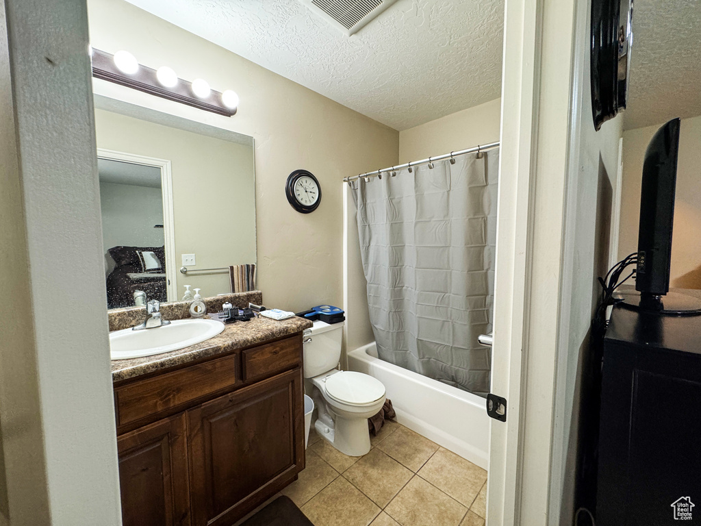 Full bathroom featuring tile patterned flooring, vanity, visible vents, and a textured ceiling