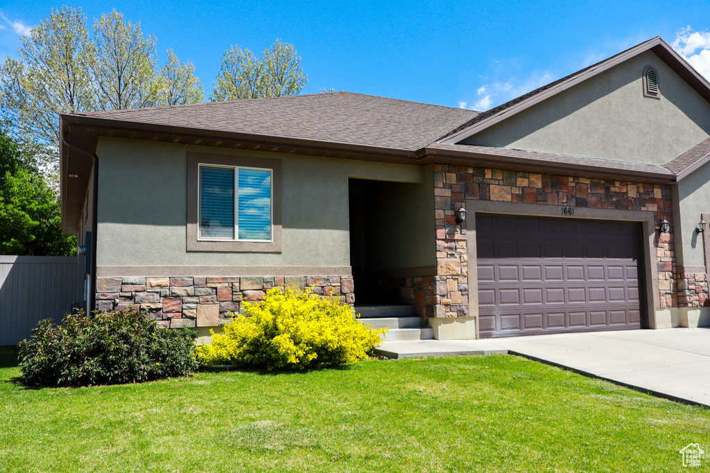 View of front of house featuring a front lawn, stone siding, stucco siding, and a garage