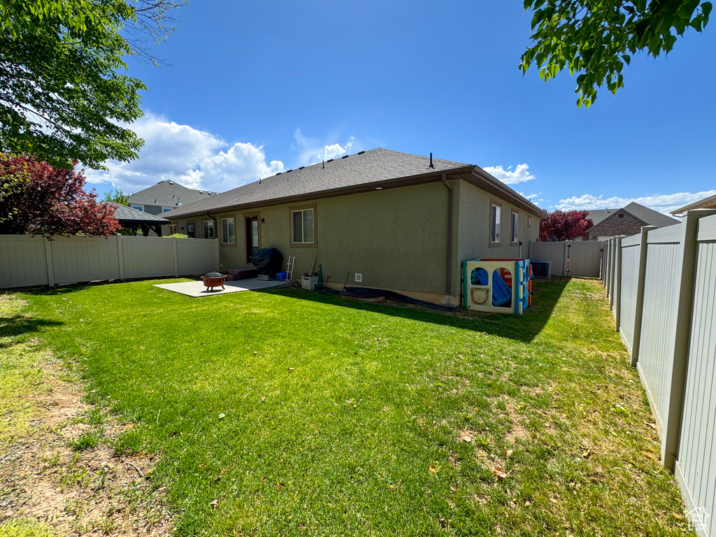 Rear view of property with an outdoor fire pit, a yard, a patio area, and a fenced backyard