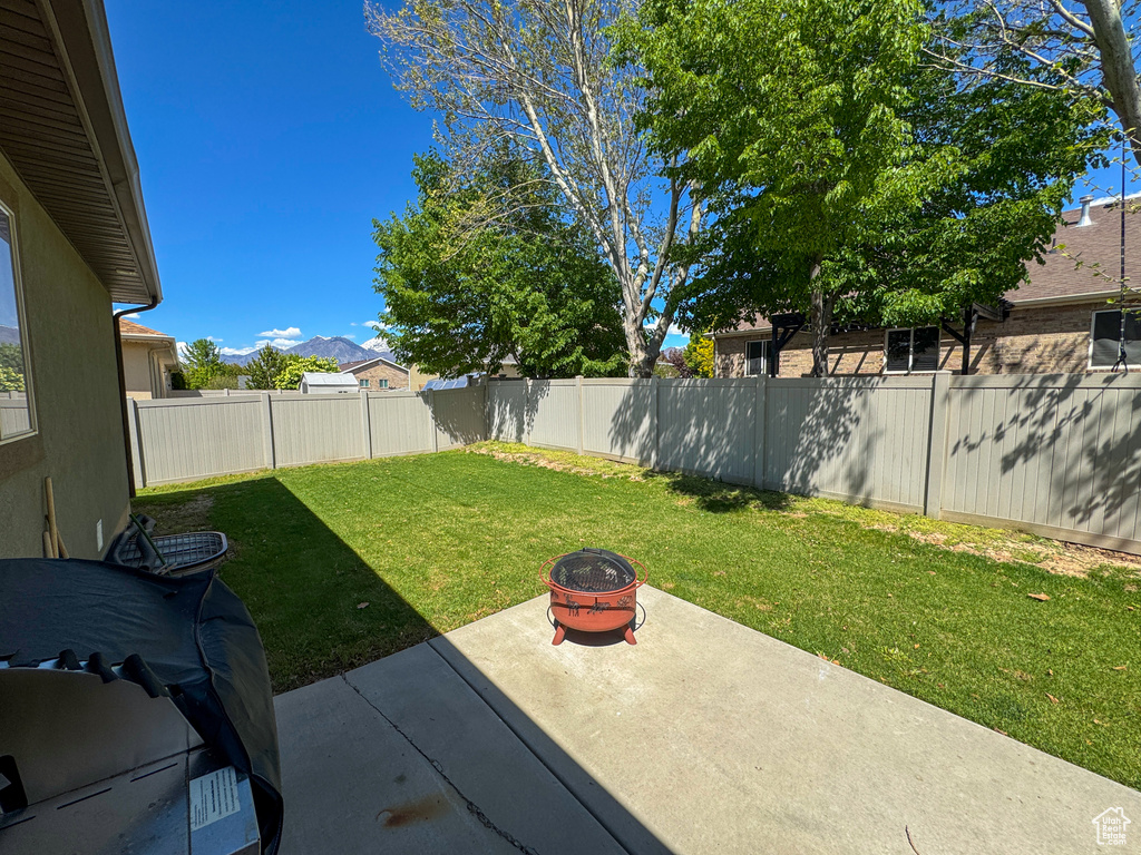 View of yard featuring a fenced backyard, an outdoor fire pit, a patio area, and a mountain view