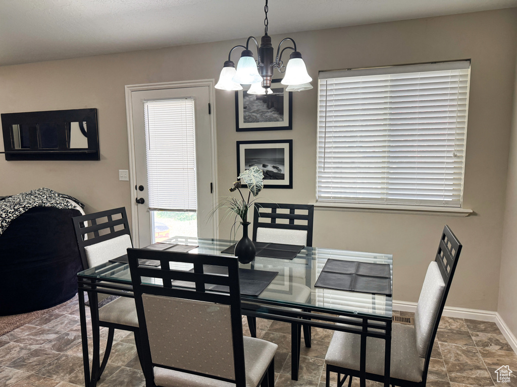 Dining room featuring an inviting chandelier, baseboards, and stone finish floor