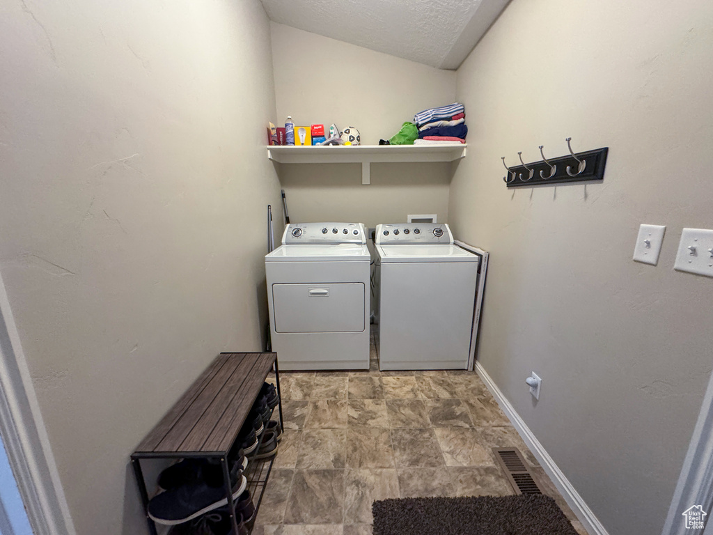 Laundry area with washer and dryer, laundry area, stone finish floor, visible vents, and baseboards