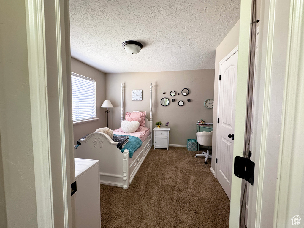 Bedroom featuring baseboards, dark colored carpet, and a textured ceiling
