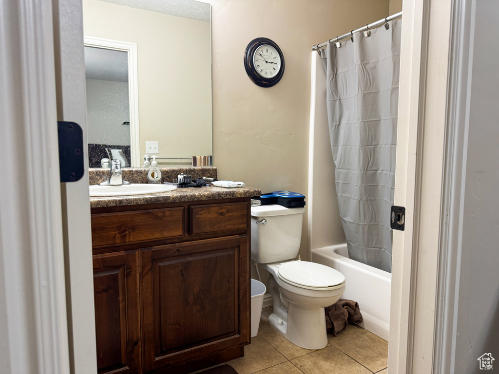 Full bath with toilet, shower / tub combo with curtain, tile patterned floors, and vanity