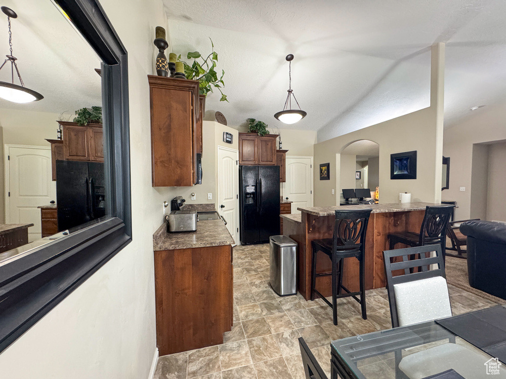 Kitchen featuring black fridge, a kitchen breakfast bar, arched walkways, and pendant lighting