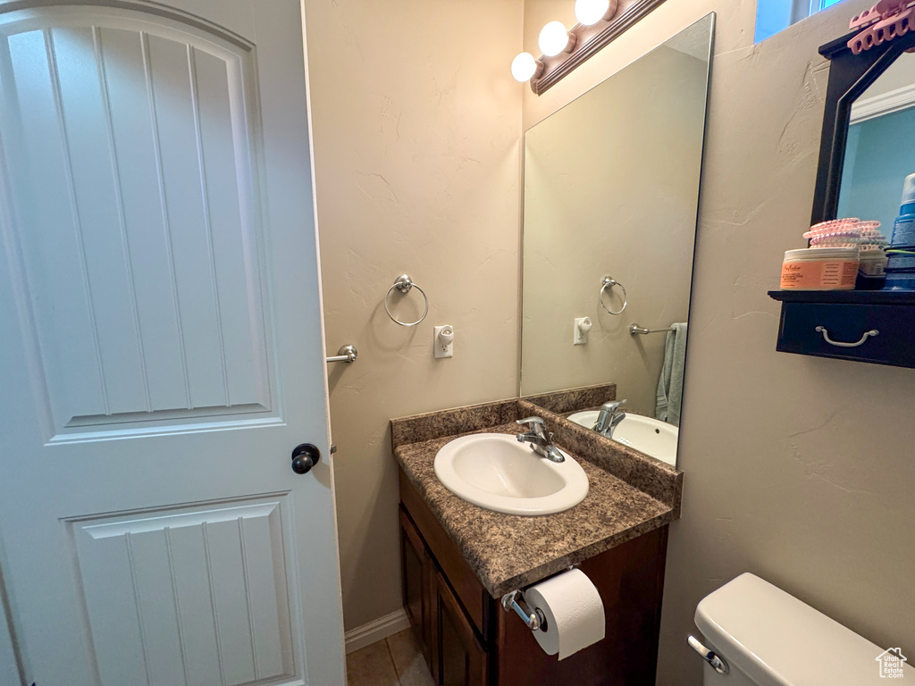 Half bathroom featuring vanity, toilet, and tile patterned floors