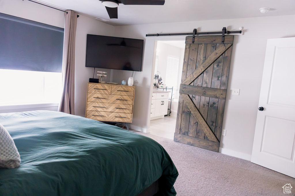 Bedroom with a barn door, light carpet, and a ceiling fan
