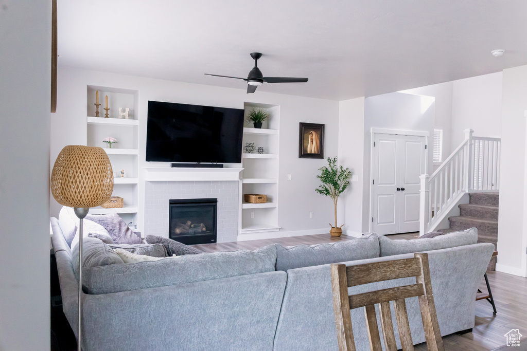 Living area with ceiling fan, wood finished floors, baseboards, and a fireplace