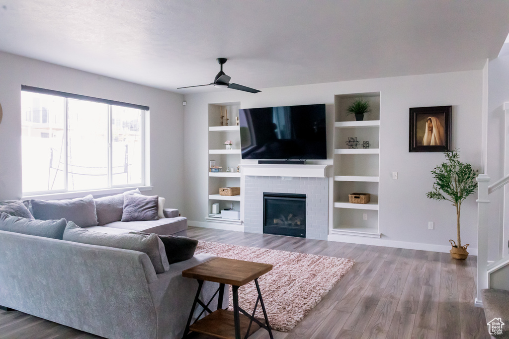 Living area with a fireplace, wood finished floors, baseboards, a ceiling fan, and built in features