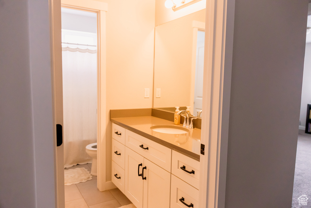 Bathroom with toilet, vanity, tile patterned floors, and curtained shower