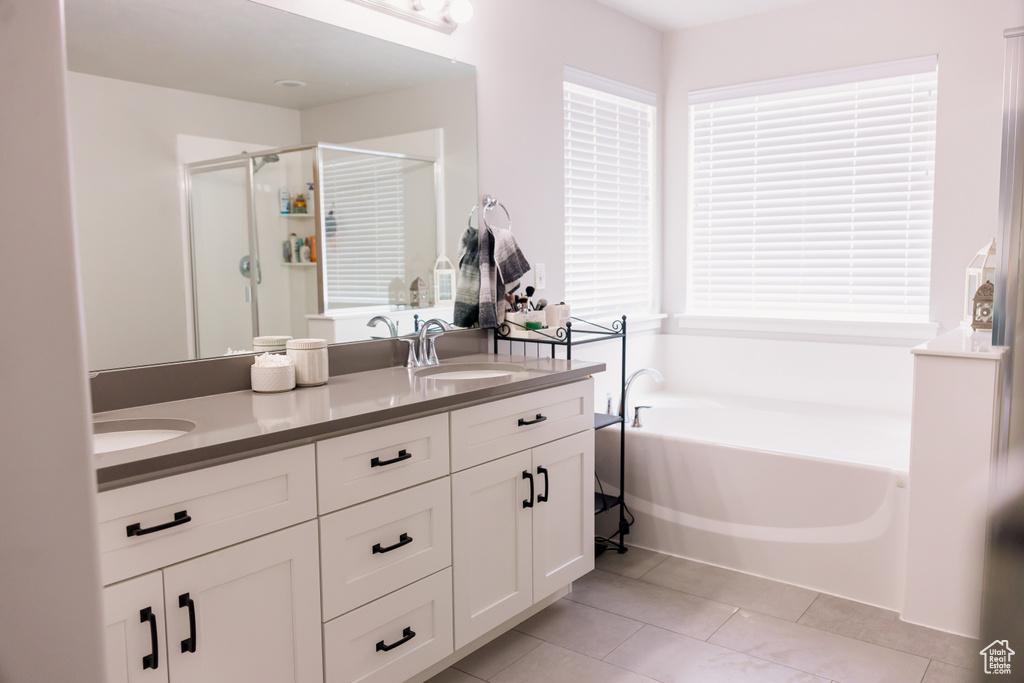 Bathroom with a shower stall, a bath, double vanity, and tile patterned floors