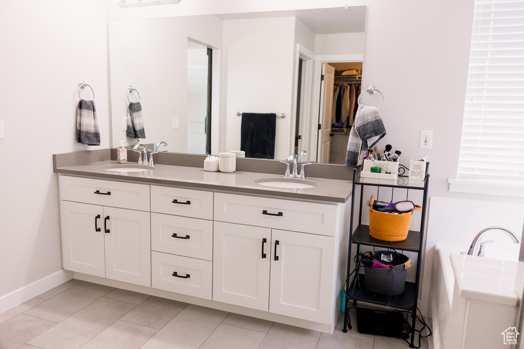 Bathroom with double vanity, tile patterned floors, baseboards, and a spacious closet