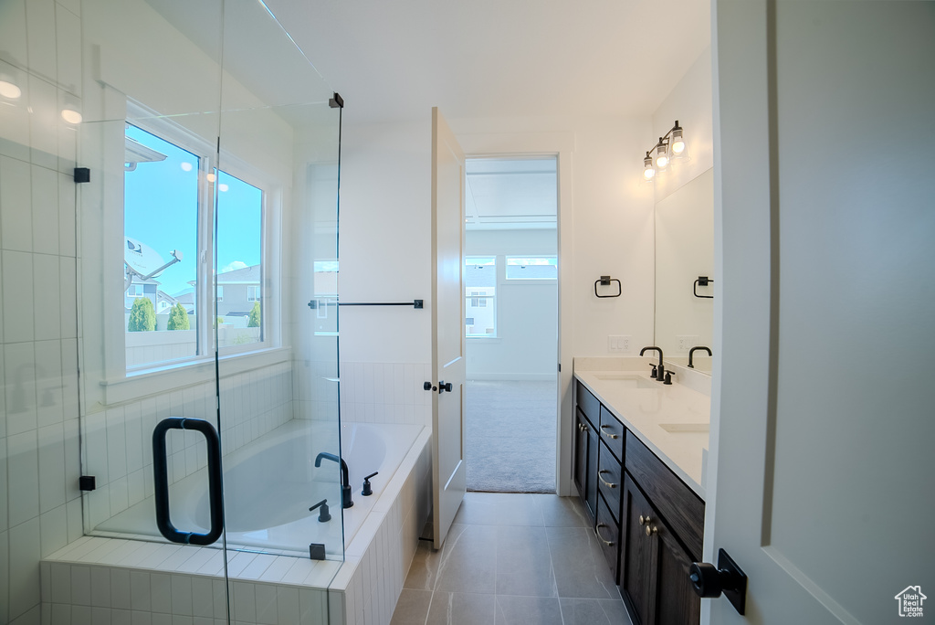 Bathroom with plenty of natural light, tiled bath, double vanity, and tile patterned flooring