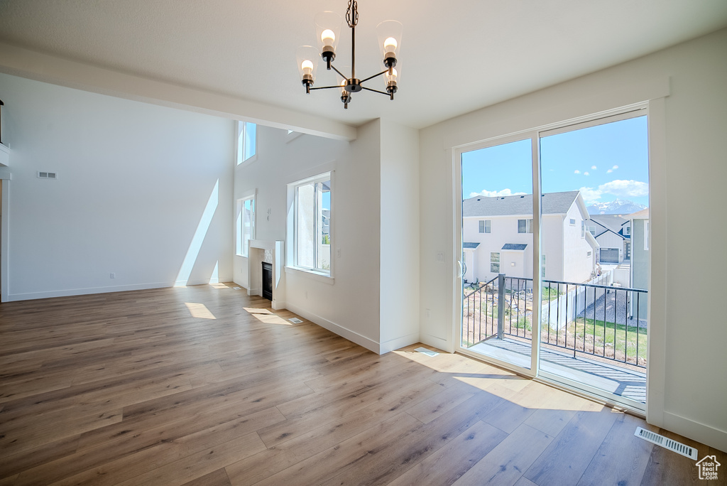 Unfurnished dining area featuring a chandelier, hardwood / wood-style flooring, a fireplace, and baseboards