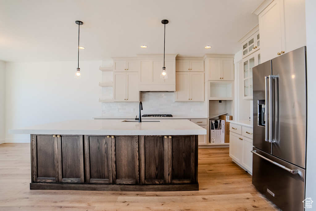 Kitchen featuring high end fridge, open shelves, a sink, light countertops, and recessed lighting