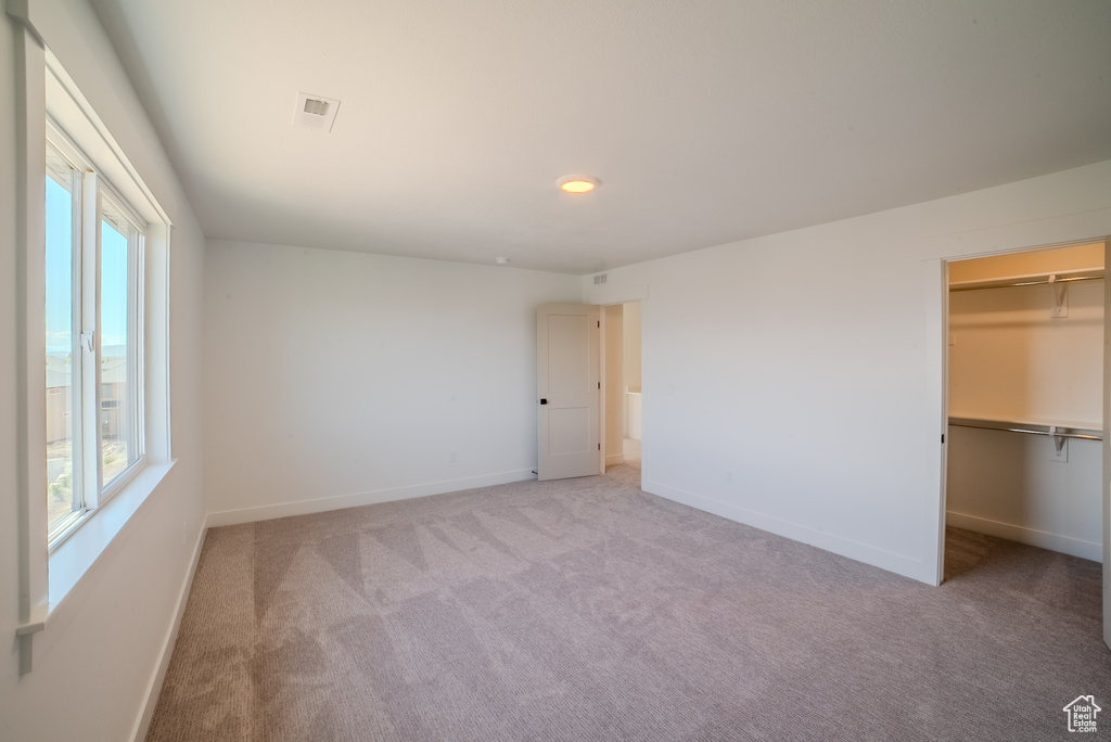Unfurnished bedroom featuring multiple windows, carpet, and baseboards