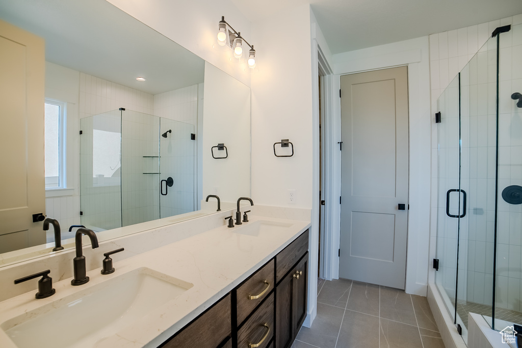Full bathroom featuring a stall shower, double vanity, and tile patterned floors