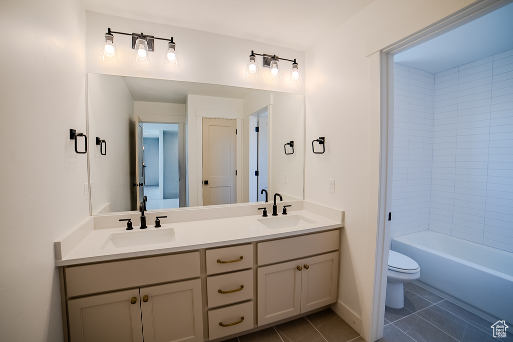 Full bath featuring tile patterned floors, toilet, double vanity, and baseboards