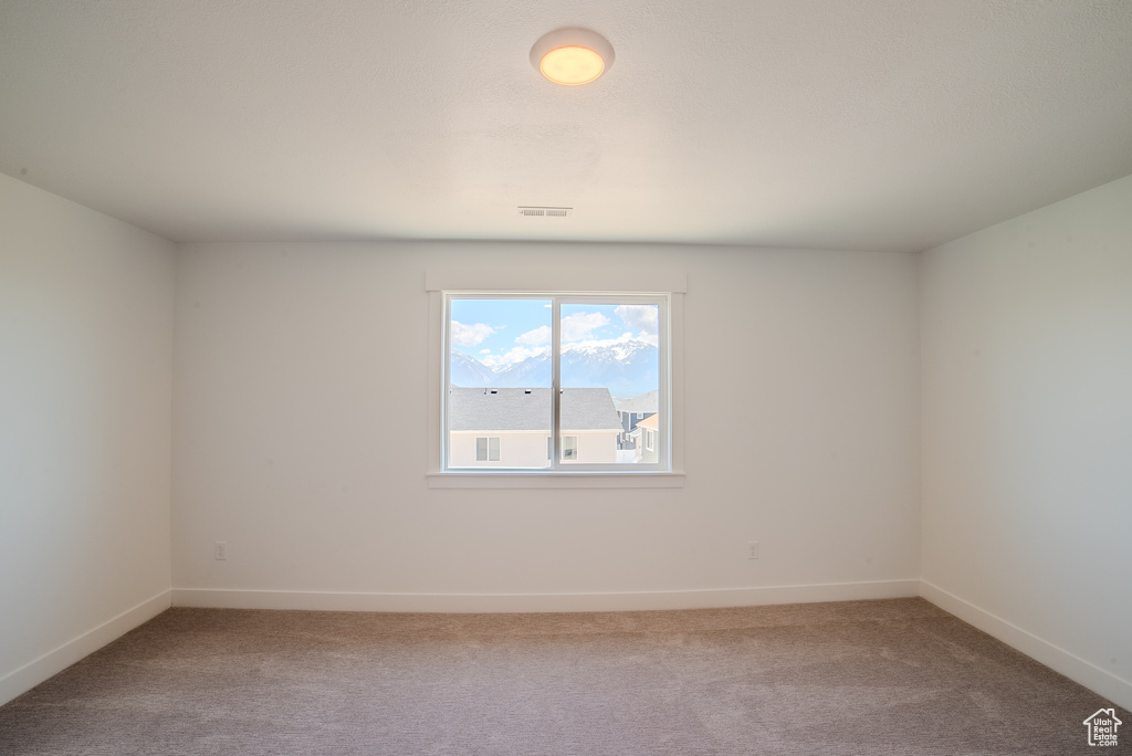 Unfurnished room featuring light carpet and baseboards