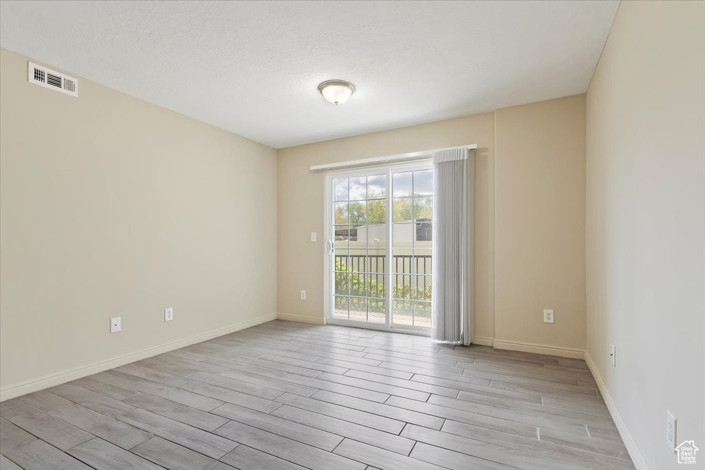 Unfurnished room featuring visible vents, light wood-style flooring, and baseboards
