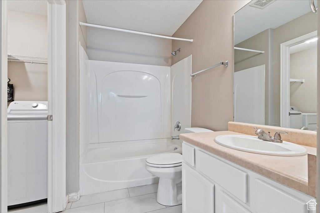 Full bath featuring washing machine and clothes dryer, washtub / shower combination, tile patterned flooring, vanity, and toilet