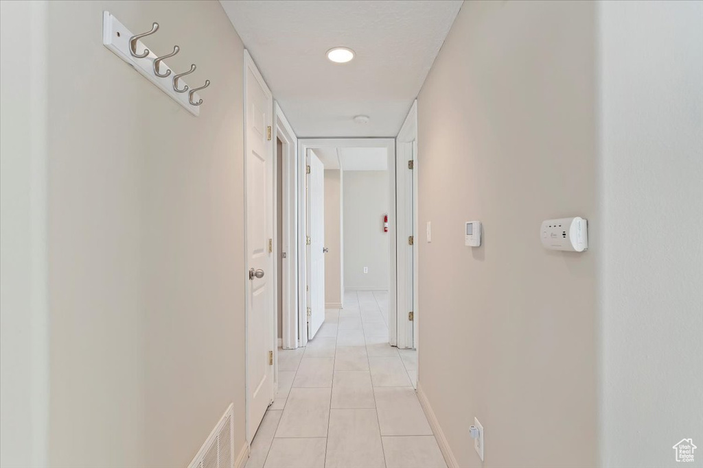 Hall with baseboards, visible vents, and light tile patterned floors