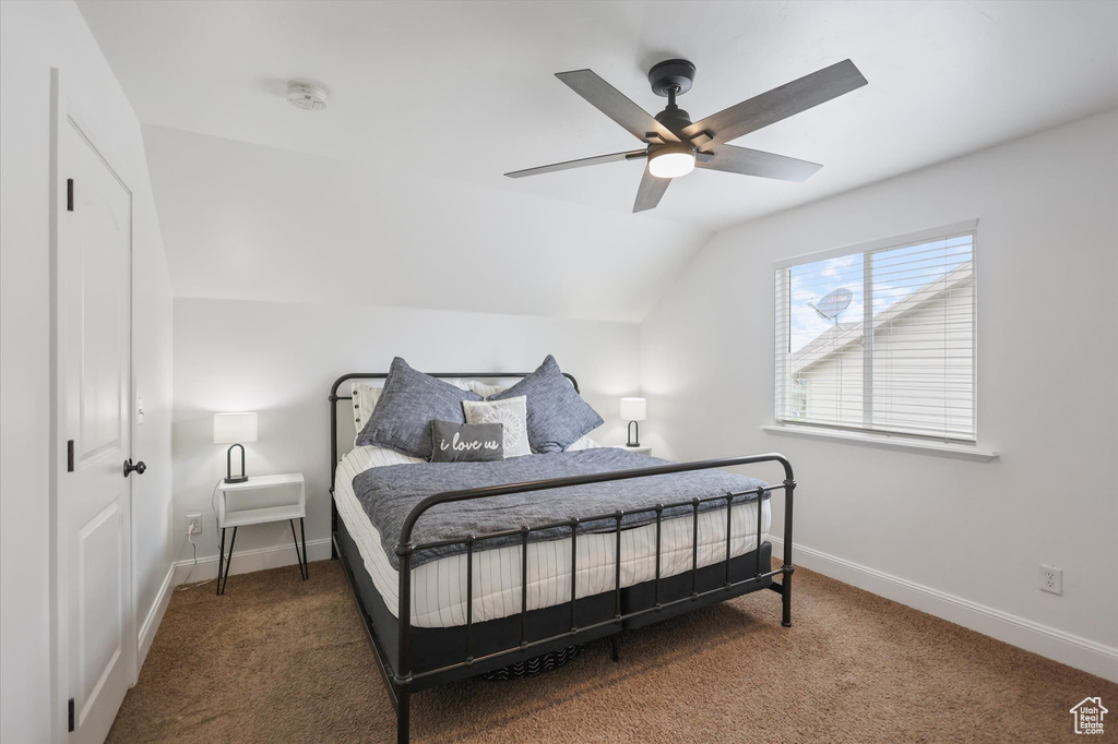 Carpeted bedroom with lofted ceiling, baseboards, and ceiling fan
