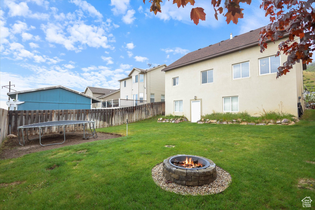 View of yard featuring a trampoline and a fire pit