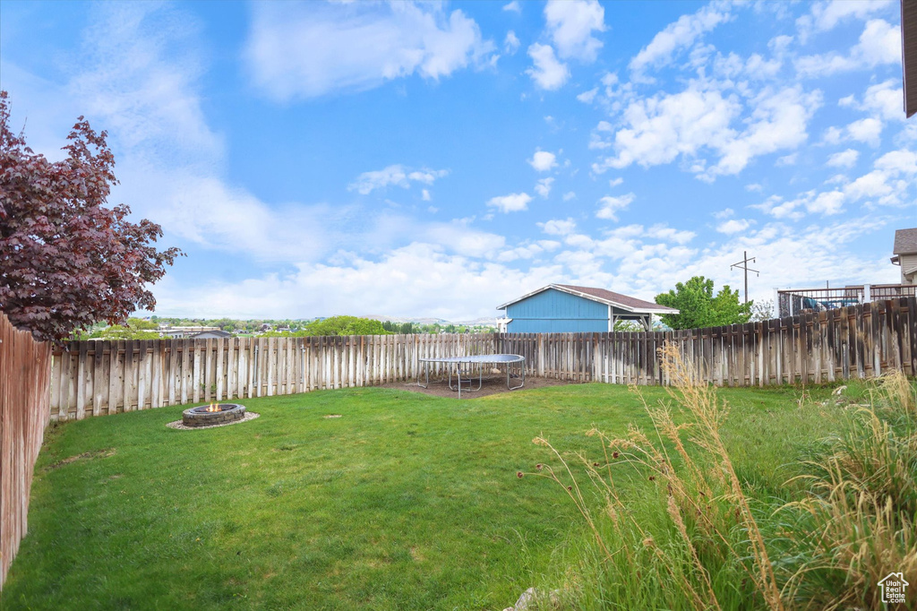 View of yard featuring a fire pit and a trampoline