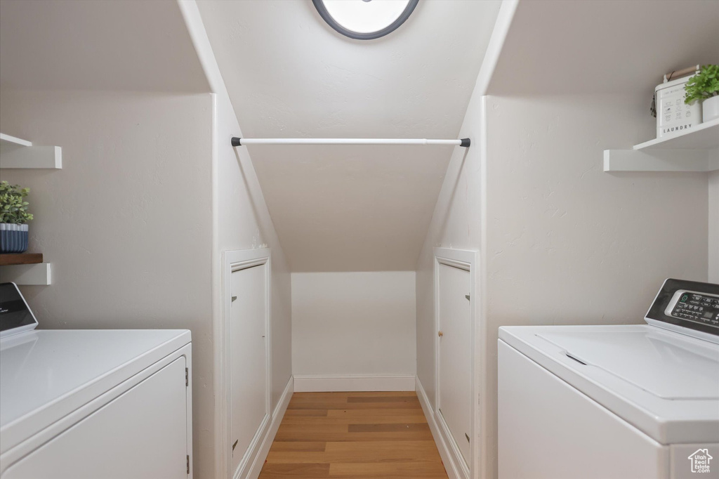 Laundry area with independent washer and dryer and light wood-style floors