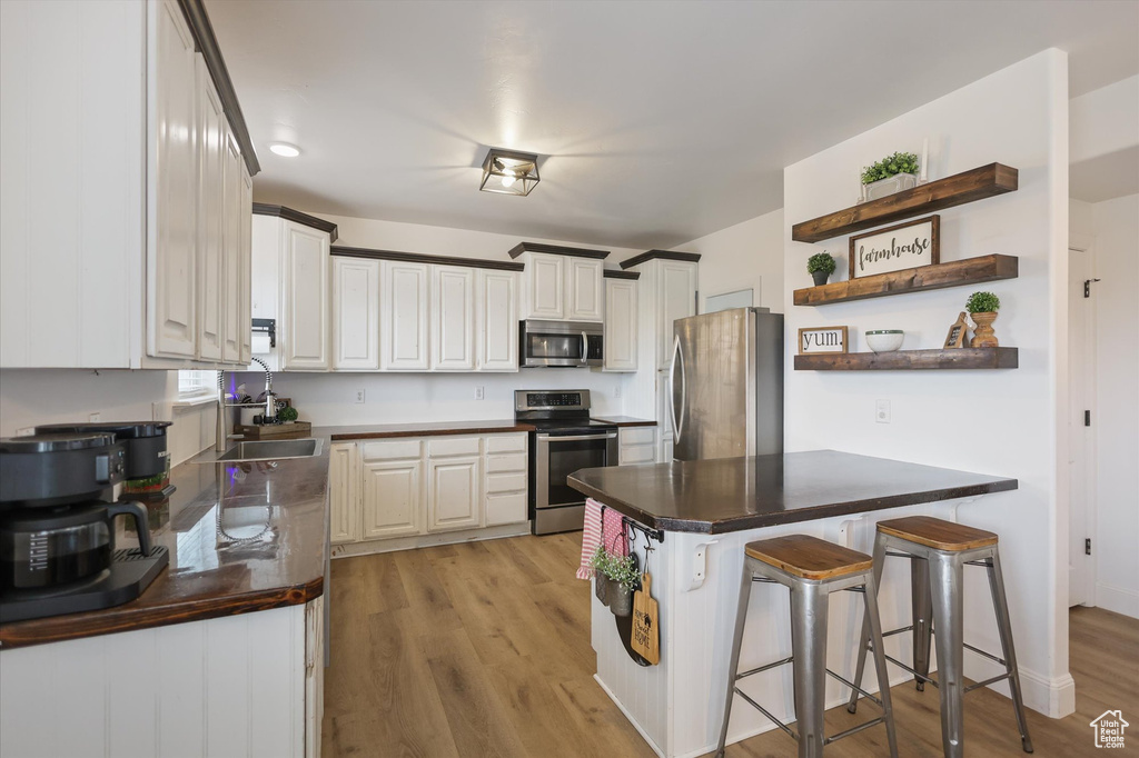 Kitchen with stainless steel appliances, open shelves, a peninsula, a breakfast bar area, and a sink
