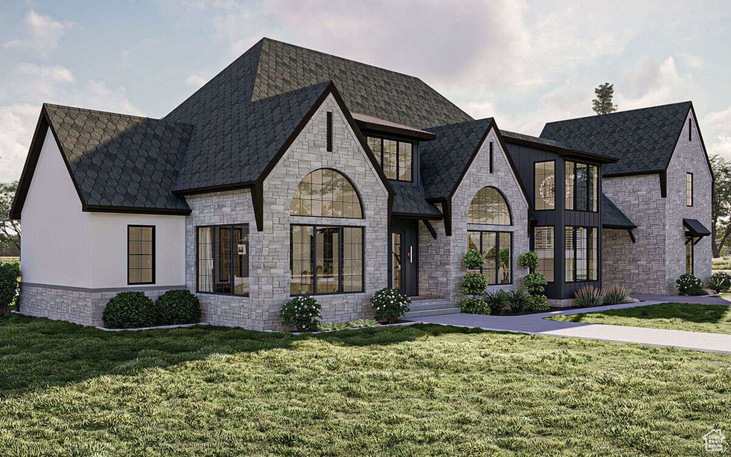 French country inspired facade with roof with shingles, a front yard, and stone siding