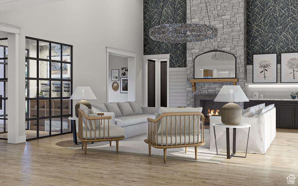 Living area with a fireplace, light wood-type flooring, and a towering ceiling