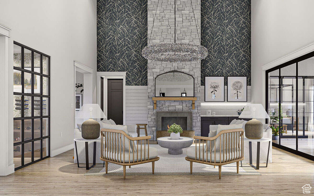 Living room with a stone fireplace, plenty of natural light, a towering ceiling, and wood finished floors