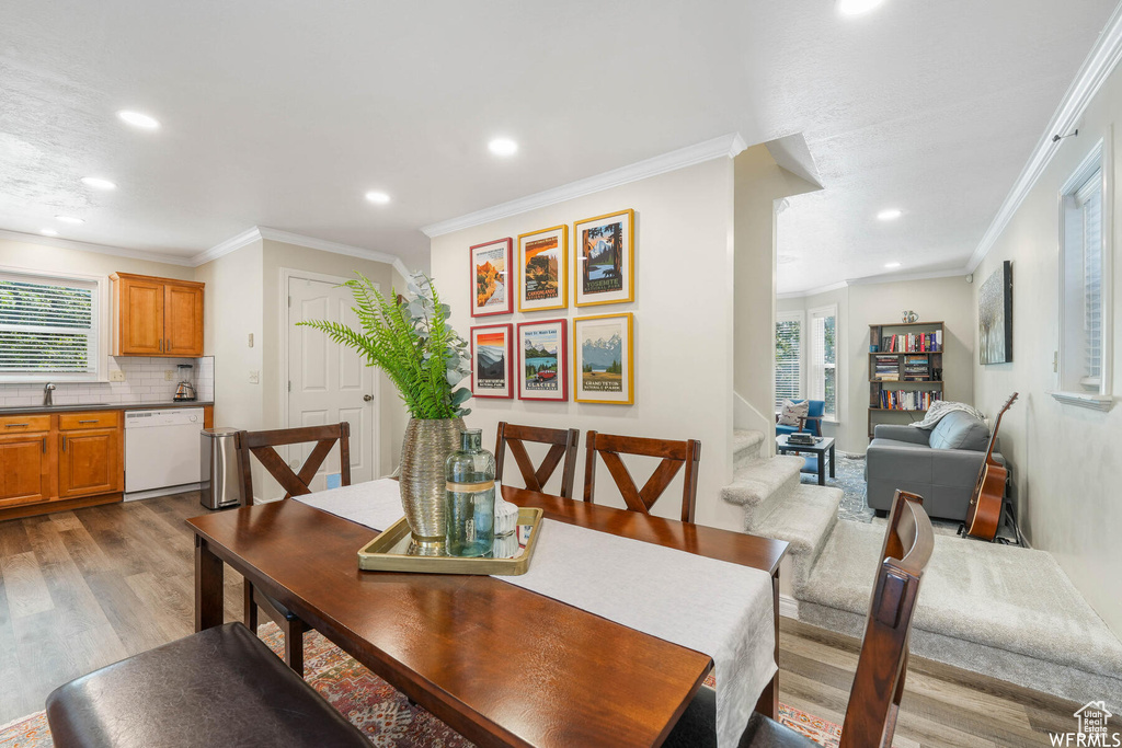 Dining space featuring wood finished floors, crown molding, and recessed lighting