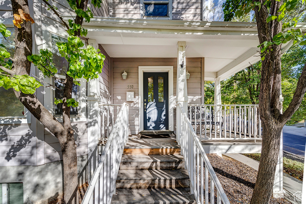 Entrance to property featuring covered porch and mansard roof