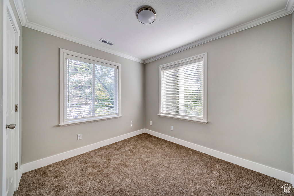 Unfurnished room featuring dark carpet, ornamental molding, and baseboards
