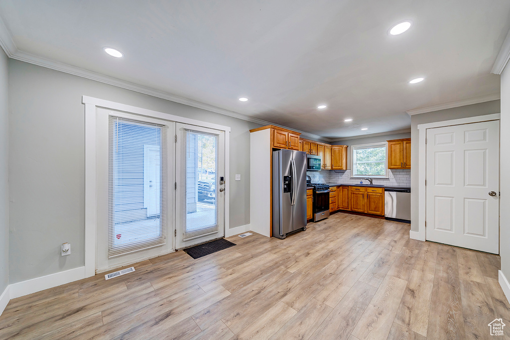 Kitchen featuring appliances with stainless steel finishes, crown molding, light wood-type flooring, a sink, and recessed lighting