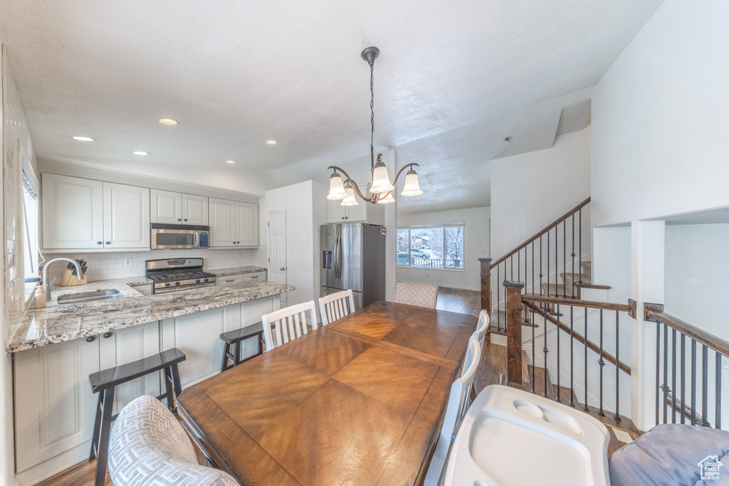 Dining space featuring a chandelier, dark wood finished floors, recessed lighting, and stairway